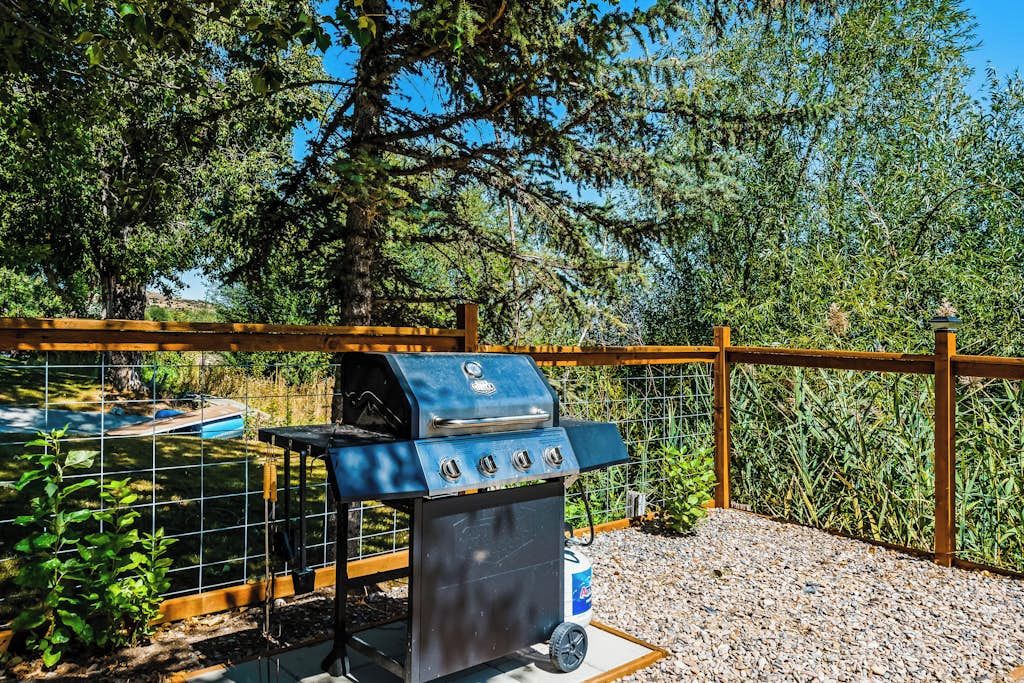 A barbecue grill with a metal grate, a control panel, and a fuel tank.