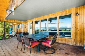 A wooden deck with a table and chairs, large windows, and a view of the outdoors. - On the Waterfront - Lakefront with Mountain Views (Fish Haven)