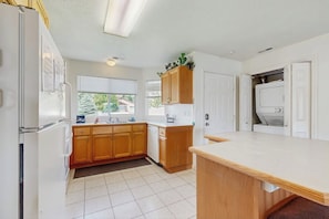 A kitchen with wooden cabinets, a white countertop, and a built-in oven. - Tennis Court Condo - Lake Views, Pool & Hot Tub (Garden City)
