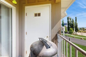 A white door with a vent, a metal object on the porch, and a view of a road and trees. - Tennis Court Condo - Lake Views, Pool & Hot Tub (Garden City)