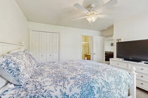 A bedroom with a bed, a television, a ceiling fan, and a door leading to another room. - Tennis Court Condo - Lake Views, Pool & Hot Tub (Garden City)