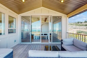 Un espacio al aire libre techado con techo de madera, una puerta de cristal que da a un interior y vistas del exterior.