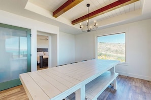 Una habitación amplia con una gran mesa de madera, una araña y vistas a un paisaje desértico.