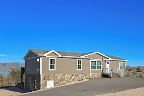 A two-story building with a stone foundation, a flat roof, and a front entrance with a staircase. - Secluded Sunrise - Lake Views, Sleeps 23, Dogs OK (Garden City)