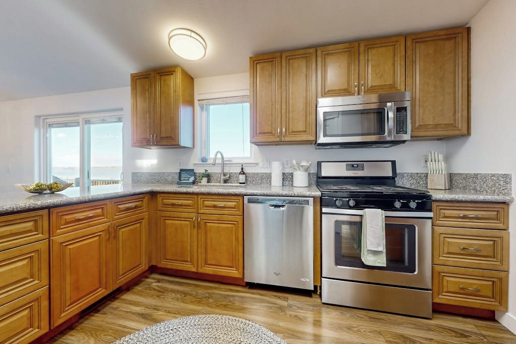 A kitchen with wooden cabinets, stainless steel appliances, a dishwasher, and a granite countertop.