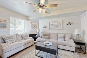 A living room with two sofas, a coffee table, a ceiling fan, and wall-mounted lamps. - Bear Lake Blue - Lake Views, Heated Pool, Hot Tub (Garden City)
