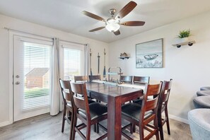 A dining area with a wooden table and chairs, a ceiling fan, and a window with blinds. - Bear Lake Blue - Lake Views, Heated Pool, Hot Tub (Garden City)