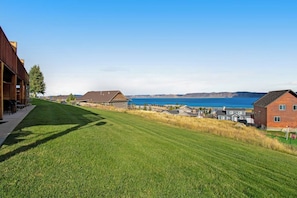 A residential area with houses, a grassy lawn, and a view of the water. - Bear Lake Blue - Lake Views, Heated Pool, Hot Tub (Garden City)
