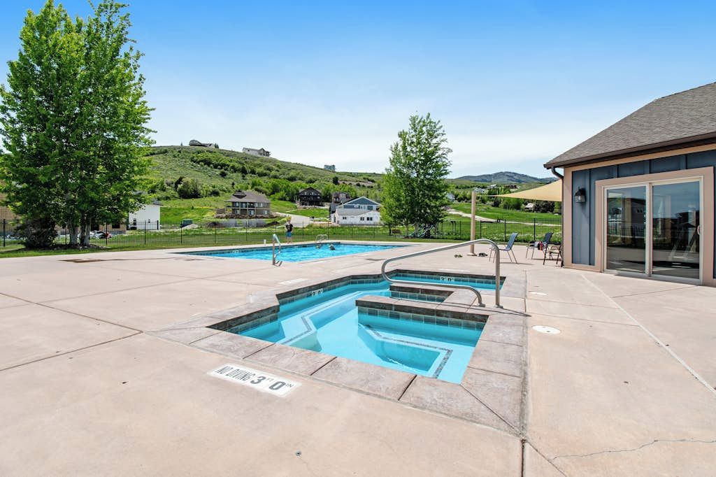 Una piscina con una vista despejada del paisaje circundante, incluyendo casas y una colina.