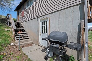 Ein Haus mit einer Haustür, einer Treppe, die zu einer Veranda führt, und einem Grill vor der Tür.
