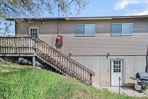 Ein zweistöckiges Haus mit einer Holztreppe zum oberen Stockwerk, einer Garagentür und einem Grill vor der Fassade.