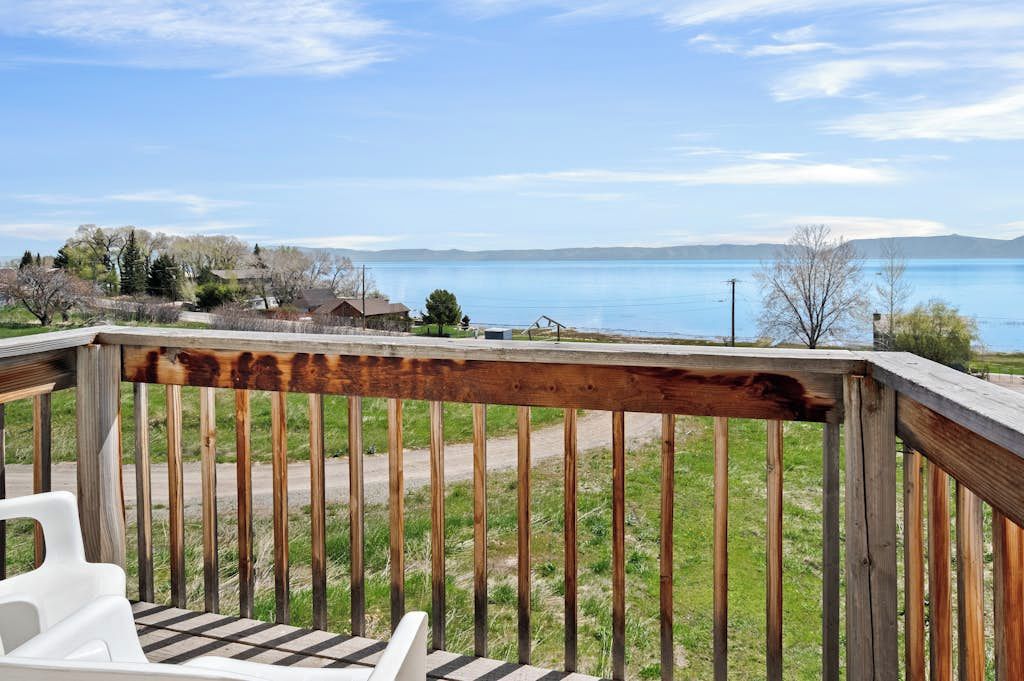 A wooden deck with a view of a lake and distant mountains.