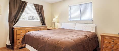 A bedroom with a large bed, wooden dresser, bedside tables, and a ceiling fan.
