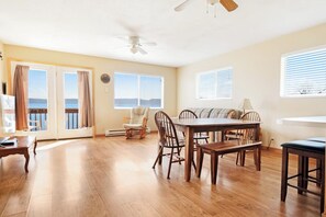 A spacious room with a wooden floor, a dining table with chairs, a sofa, and a ceiling fan. - Meadow Mountain Home (Garden City)