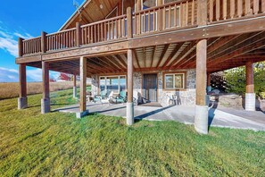 A wooden cabin with a balcony, stone walls, and outdoor seating. - Elk Ridge Lodge - Log Cabin with Lake Views (Garden City)