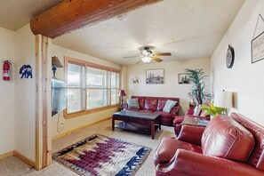 A living room with a red leather sofa, a coffee table, and a patterned rug. - Elk Ridge Lodge - Log Cabin with Lake Views (Garden City)