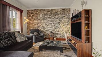 A living room with a stone wall, a sofa, a chair, a coffee table, and a TV stand.