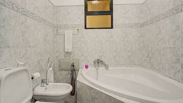 Une salle de bain avec une baignoire, des toilettes et un bidet.