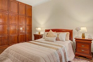 A bedroom with a large wooden wardrobe, a bed with multiple pillows, and two bedside tables with lamps. - Holiday Home 'Vista Atlântica Garachico' with Sea View, Private Terrace & Wi-Fi (Câmara de Lobos)