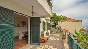A courtyard with a tiled floor, a wooden bench, and a table with chairs. - Holiday Home 'Vista Atlântica Garachico' with Sea View, Private Terrace & Wi-Fi (Câmara de Lobos)