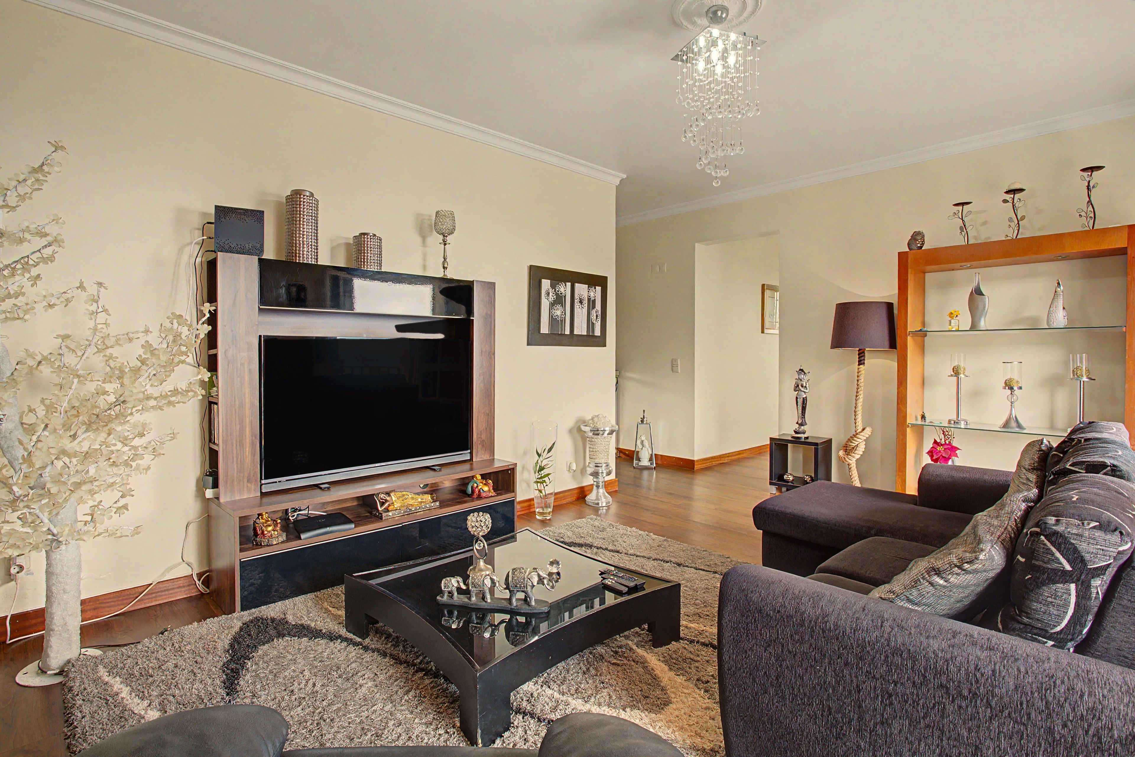 Ein Wohnzimmer mit Flachbildfernseher, Sofa, Couchtisch und Dekorationselementen.