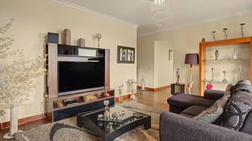 Ein Wohnzimmer mit Flachbildfernseher, Sofa, Couchtisch und Dekorationselementen.