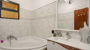 A bathroom with a bathtub, a vanity with a mirror, and a wooden cabinet. - Holiday Home 'Vista Atlântica Garachico' with Sea View, Private Terrace & Wi-Fi (Câmara de Lobos)