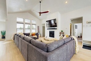 Ein modernes Wohnzimmer mit einer großen Eckcouch, einem Kamin und einem an der Wand befestigten Fernseher.