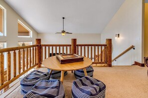 Ein Zimmer mit einer Holztreppe, einem runden Tisch mit einem Buch und zwei Sitzsäcken.