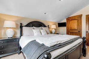 Ein Schlafzimmer mit einem Bett, Nachttischen, Lampen, einem Fernseher und einem Kleiderschrank.