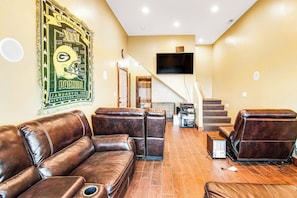 A living room with leather sofas, a flat-screen TV mounted on the wall, and a staircase leading to another level. - Mountain View Escape (Garden City)