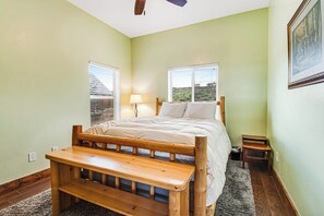 A bedroom with a wooden bed, a bench, a nightstand, and a window with a view. - Mountain View Escape (Garden City)