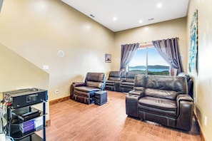 A living room with leather sofas, a flat-screen TV, and a large window with curtains. - Mountain View Escape (Garden City)