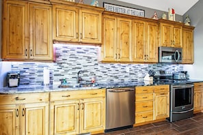A kitchen with wooden cabinets, a stainless steel dishwasher, and a tiled backsplash. - Mountain View Escape (Garden City)