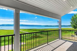 A covered balcony with a view of a lake and distant mountains. - Lakefront Retreat - Hot Tub, Game Room & Fire Pit (Garden City)