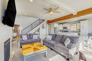 A modern living room with two grey sofas, a wooden coffee table, and a ceiling fan. - Lakefront Retreat - Hot Tub, Game Room & Fire Pit (Garden City)