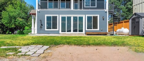 A two-story house with a balcony, large windows, and a fenced yard.