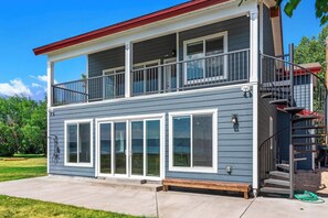 A two-story building with a balcony, a staircase, and a front door. - Lakefront Retreat - Hot Tub, Game Room & Fire Pit (Garden City)