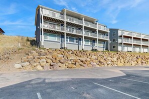 A multi-story building with balconies, a parking lot, and a stone retaining wall. - Bear Lake  View - Pool, Hot Tub & Game Room (Garden City)