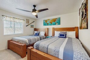 A bedroom with two wooden beds, a ceiling fan, a window with blinds, and a world map artwork on the wall. - Bear Lake  View - Pool, Hot Tub & Game Room (Garden City)