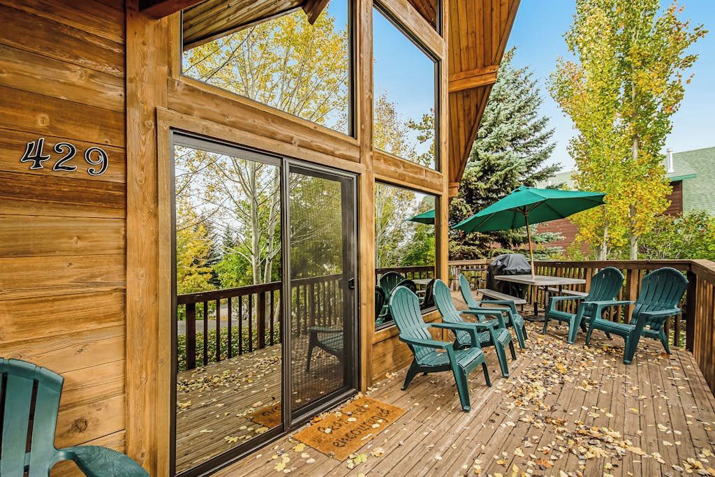 Une terrasse en bois avec des sièges d’extérieur et une grande porte-fenêtre coulissante.