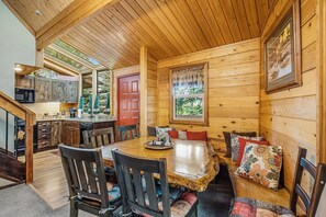 Ein Holzblock-Interieur mit Essbereich, Küche und einer roten Tür.
