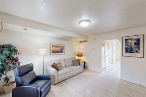A living room with a sofa, a lamp, a potted plant, and a framed picture on the wall. - Marina Retreat - Lake Views, Hot Tub & Tennis (Garden City)