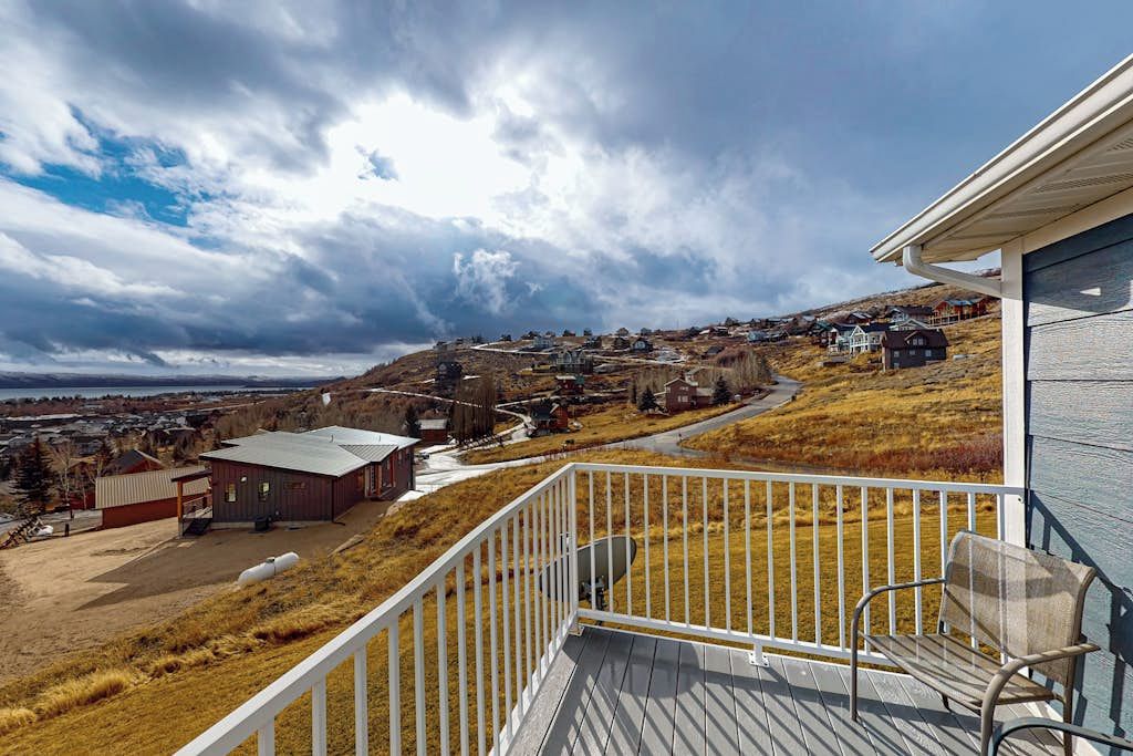 A balcony with a view of a rural landscape, including houses and a body of water.