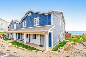 Une maison à deux étages avec un porche avant couvert, un garage et une vue sur un lac.