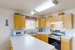 Une cuisine avec des meubles en bois, un four à micro-ondes, une cuisinière et une fenêtre donnant sur un beau paysage.