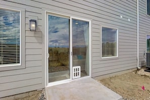 Uma casa com porta de vidro deslizante, um pequeno alpendre e uma janela com persianas.