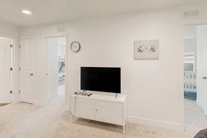 A room with a white entertainment unit, a flat-screen TV, a clock, and a framed picture on the wall. - Garden City Glee - Mountain Views, Dogs Welcome (Garden City)