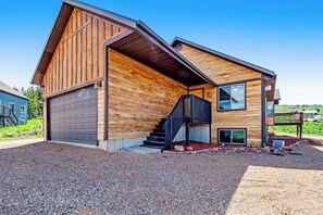 Ein modernes, zweistöckiges Haus mit Holzfassade, einer Garage und einer Treppe, die zum zweiten Stock führt.