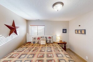Une chambre à coucher avec un lit, une décoration en forme d’étoile sur le mur, une fenêtre et une table de chevet avec une lampe.